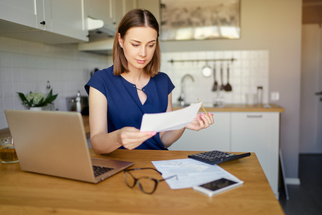 woman reviewing documents at her kitchen table to figure out how to lower property taxes