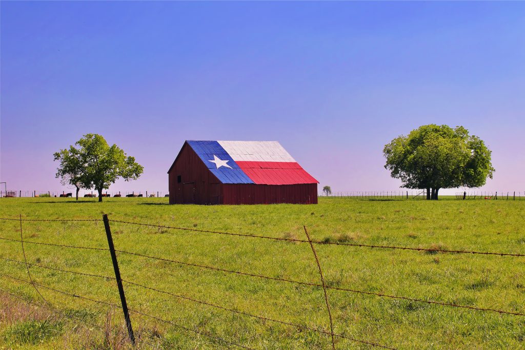 A barn on a Texas ranch with the state flag painted on the roof to ask, why are Texas property taxes so high