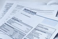 Monthly mortgage statement with home insurance policy papers to monitor for a mortgage escrow shortage